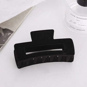 Detail of a large black velvet flocked geometric hair claw clip on a stylish desk setting