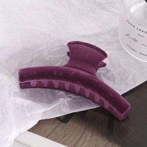 Detail of large purple flocked hair claw clip on white paper with soft textured finish