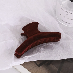 Deep red flocked velvet hair claw clip with geometric curved design on white background
