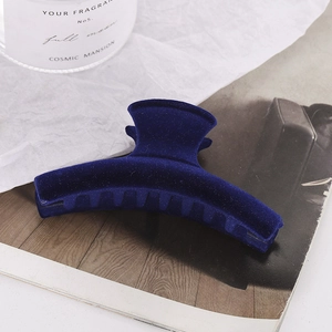 Large dark blue flocked crescent hair claw clip for women on a minimalist background