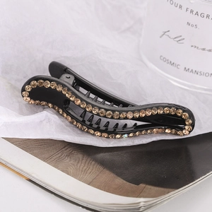 Close-up of black hair clip with amber rhinestones and anti-slip teeth on magazine