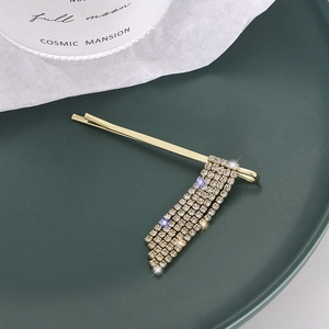 Eleganter goldener Haarclip mit Strassquasten auf einem dunkelgrünen Tablett