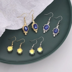 Set of four pairs of colorful drop earrings with oval gems on a green ceramic tray