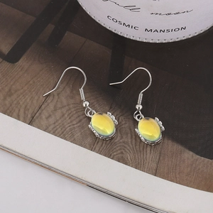 Detail view of oval iridescent stone earrings on a magazine with elegant decor