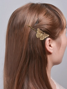 Detail van een gouden vlinder haarclip in bruin haar met fijne gravure van de vleugeltextuur