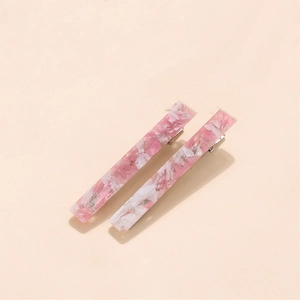 Detailed close-up of ivory pink acetate hair clips with marble floral resin texture
