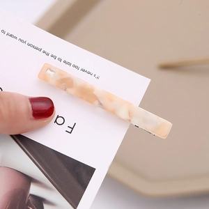 Detailed macro view of an orange marble acetate hair clip with a metal duckbill base
