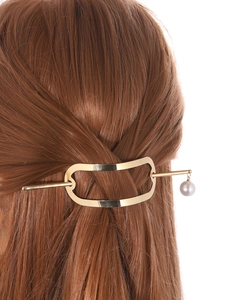Detailed view of minimalist gold hair stick with pearl drop accent in a modern updo