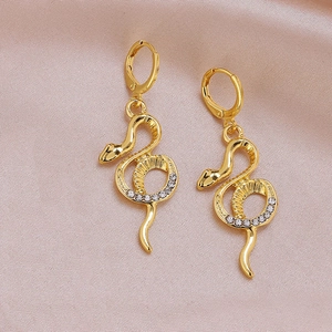 Elegant gold snake earrings with sparkling crystals displayed on soft pink silk fabric