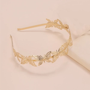 Elegante cerchietto con farfalle dorate in metallo traforato su sfondo rosa chiaro