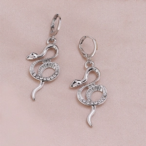 Elegant silver snake dangle earrings with sparkling crystal pavé stones on pink background