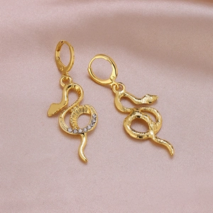 Close-up of gold snake drop earrings with sparkling crystals on soft pink silk fabric