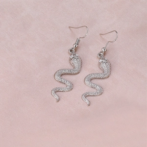 Détail de boucles d'oreilles serpent argentées avec texture d'écailles réalistes