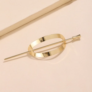 Polierter goldener Haarstab mit ovaler Hohlform auf minimalistischem beigem Hintergrund