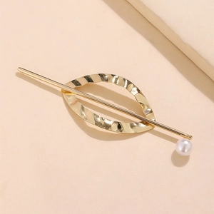 Detail view of a minimalist gold metal hair stick with wave texture and white pearl
