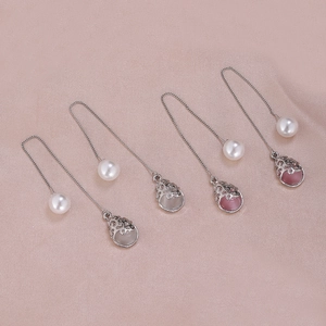 Detail of long silver threader earrings with pearls and hollow metal cages on silk
