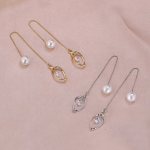 Detail of gold and silver long chain earrings with pearls and leaf pendant on pink silk