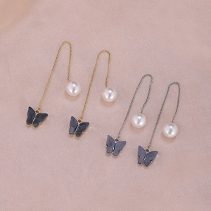Detail of moon and star butterfly pearl drop earrings in gold and silver finish