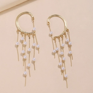 Macro detail of golden pearl tassel ear cuffs with delicate metal chains and white beads