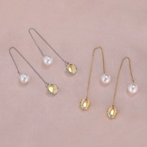 Detail of elegant gold and silver long chain earrings with pearls and yellow gemstones