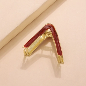 Detail view of V-shaped gold metal hair claw with marble textured dark red enamel finish
