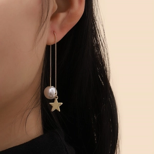 Detail of long star and pearl drop earrings shown as elegant side profile on model