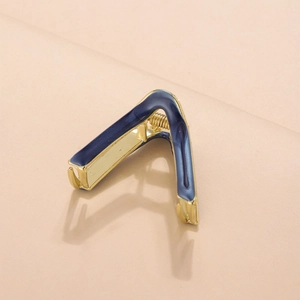 Macro shot of minimalist navy blue enamel V-shaped hair claw with gold metal spring
