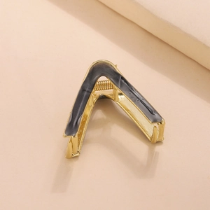 Detailed macro shot of the V-shaped metal hair claw with black marble texture finish
