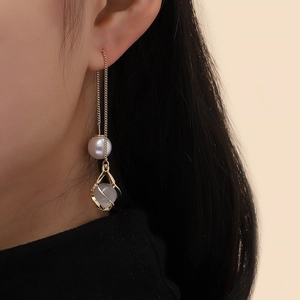 Detailed shot of long gold tassel earrings with round pearls and spiral moonstone pendants