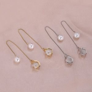 Macro detail of long chain earrings with pearls and opal stones on pink silk