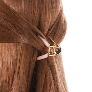 Pink and gold V-shaped metal hair claw clip styled on a woman's brown hair