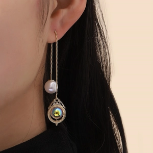 Close-up of elegant gold long chain drop earring with white pearl and opal stone on a model
