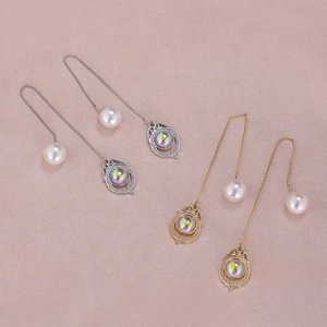 Detailed macro view of gold and silver moon star pearl long drop earrings on silk