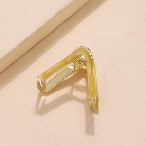 Detail shot of a V-shaped golden hair claw with yellow oil-dripped finish and metal teeth