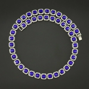 Macro detail of silver-tone Cuban link necklace with deep blue square-cut gemstones