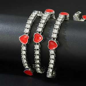 Vue détaillée de trois bracelets tennis argentés avec cœurs rouges sur un support noir