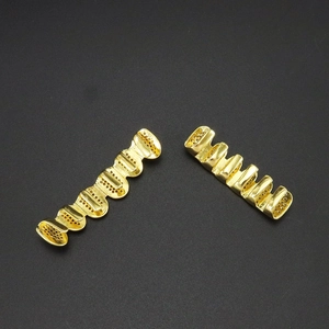 Détail de grillz dorés hip hop avec design ajouré micro-pave sur fond noir minimaliste