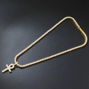 Hip hop gold tennis chain with iced out Ankh cross pendant on black background