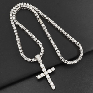 Detalle de colgante de cruz con perlas y cadena tennis brillante sobre fondo negro