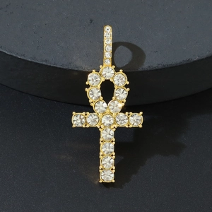 Close-up of golden Ankh cross pendant with pavé-set stones on grey stone stand