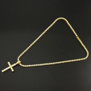 Collar de tenis dorado minimalista con colgante de cruz con perlas sobre fondo negro