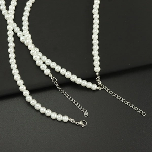 Vue détaillée du collier de perles blanches avec fermoir mousqueton argenté et chaînette