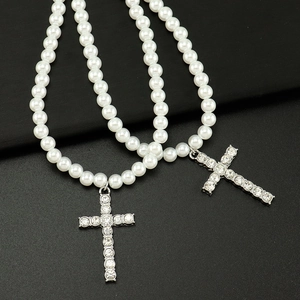 Détail de colliers de perles de luxe avec pendentifs croix sertis de strass brillants