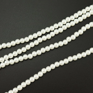 Collier avec pendentif croix en perles blanches de 8mm sur un fond sombre