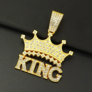Dettaglio del ciondolo a corona dorata e lettere KING con strass bianchi scintillanti