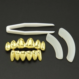 Detail view of 18k gold-plated vampire grillz set with tweezers and fixing bars