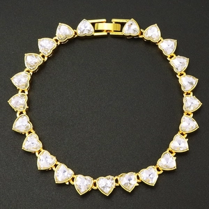 Elegant gold heart bracelet with sparkling clear crystals on a textured black surface