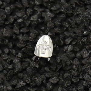Macro detail of silver hip hop grillz featuring a clear zircon inlaid cross pattern