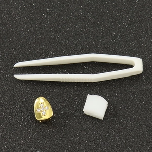Detail view of gold cross grillz set with cubic zirconia, tweezers and silicone mold