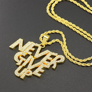 Détail du pendentif doré 'NEVER GIVE UP' avec diamants et chaîne en maille torsadée